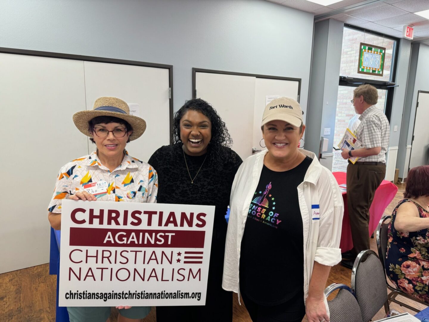 People posing together at an event holding a sign that reads "Christians Against Christian Nationalism."