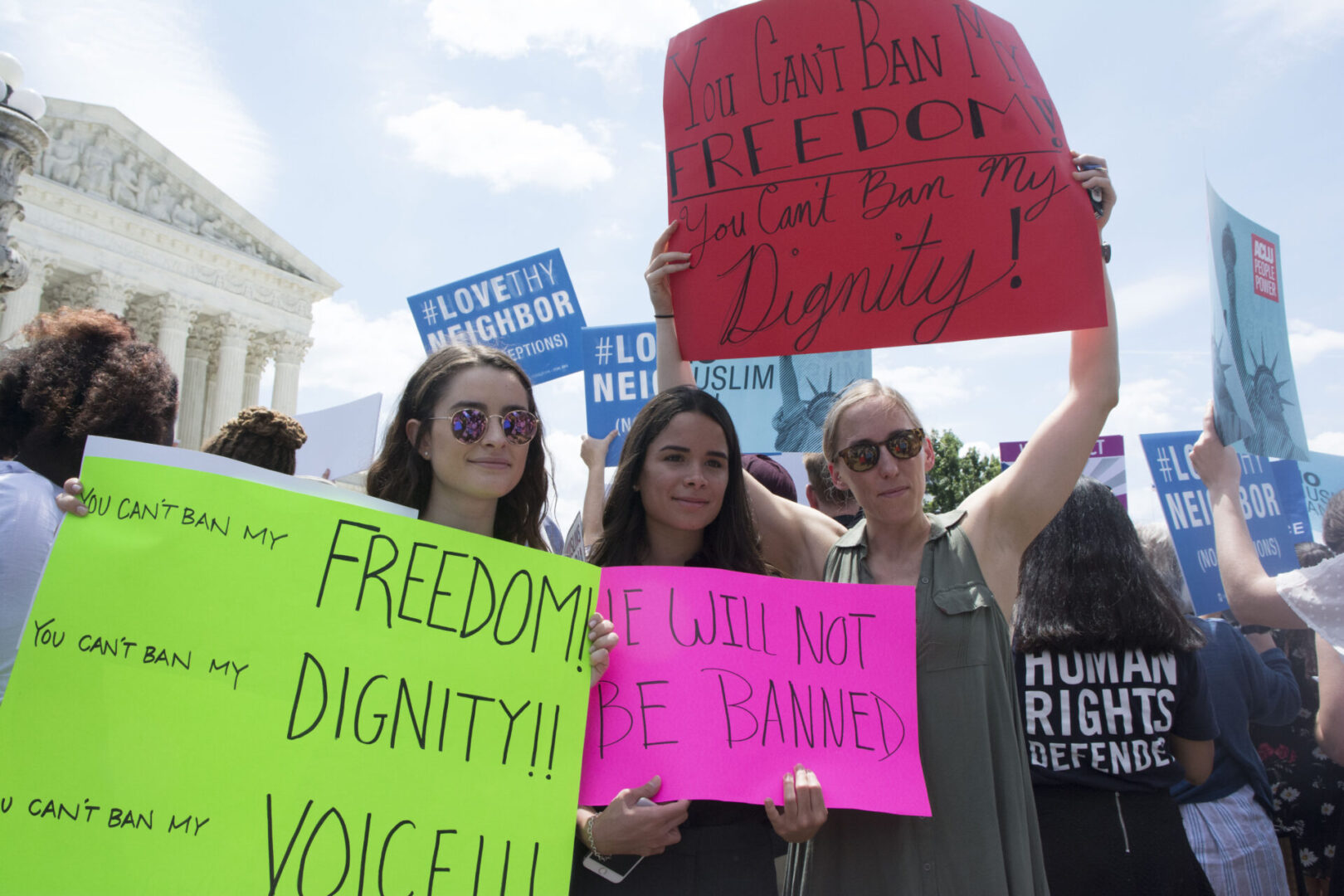 People are holding colorful protest signs advocating for freedom, dignity, and reproductive rights.