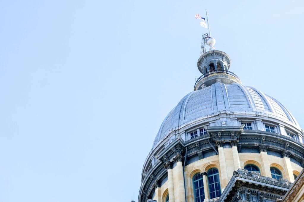 A large domed building with classical architecture stands against a clear blue sky.