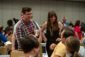People are engaged in conversation at a casual social gathering, with one individual holding a drink.
