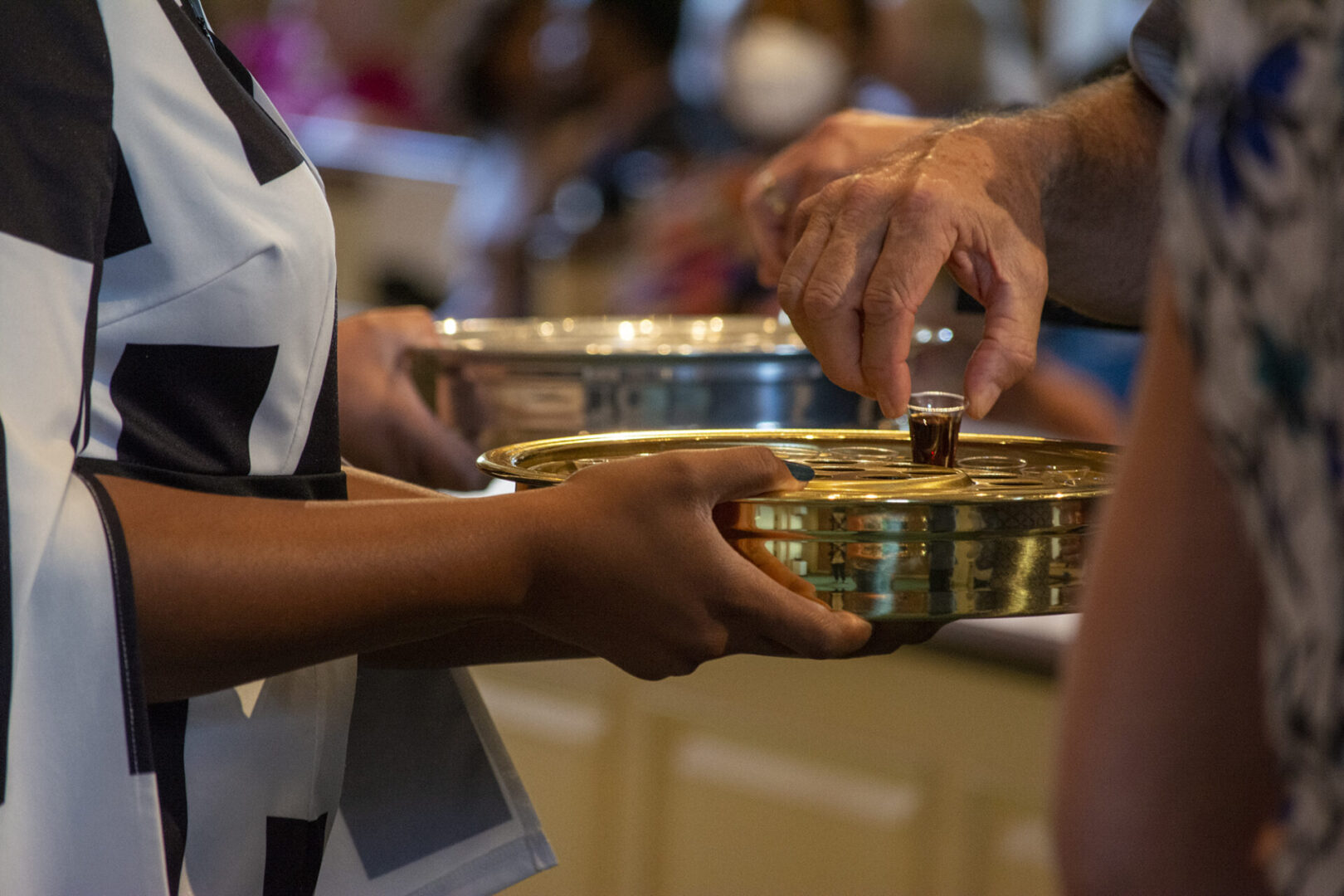 A person is passing a tray with small cups during a religious service.