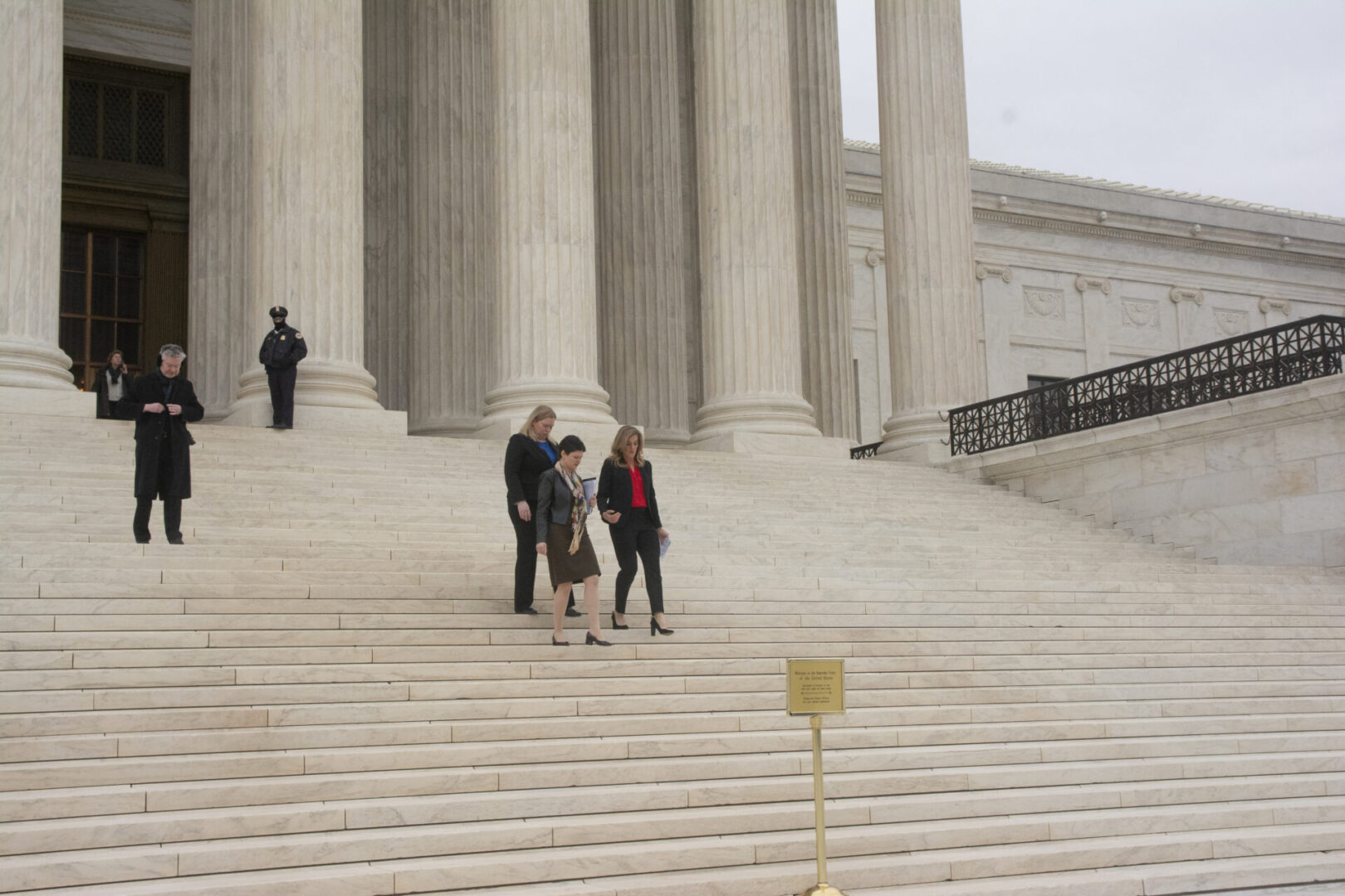 People are walking down the steps of a grand building with large columns.