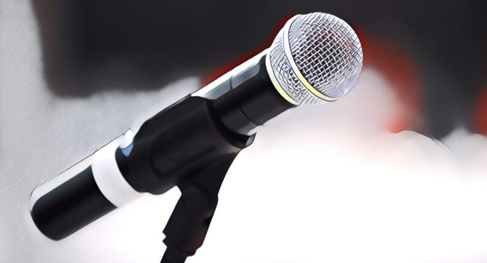 A close-up of a microphone on a stand against a blurred background.