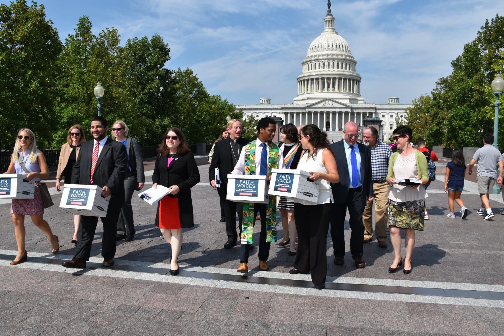 A group of people carrying signs and papers is walking near the U.S. Capitol building.