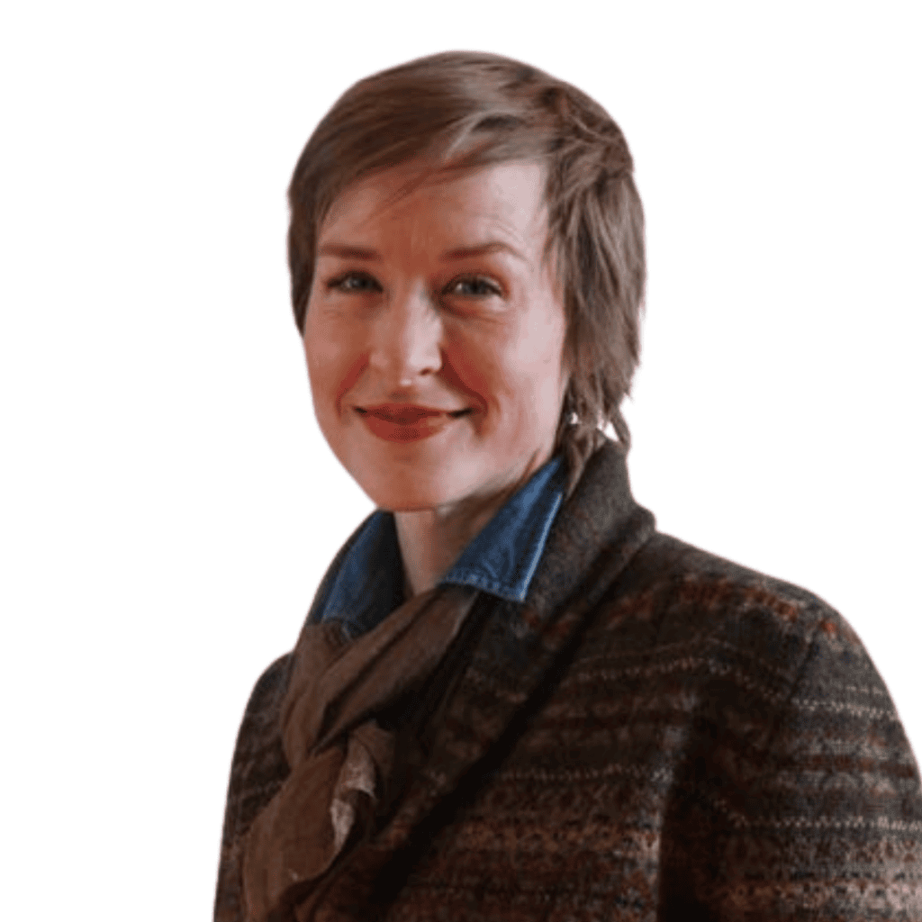 A person with short hair is wearing a brown coat and blue collar, smiling against a plain background.