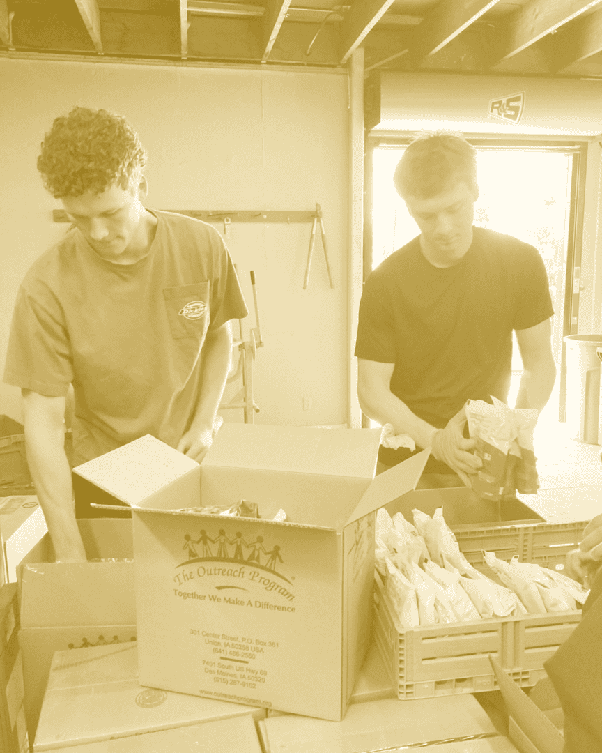 Two college students get food out of boxes to serve at a food pantry.